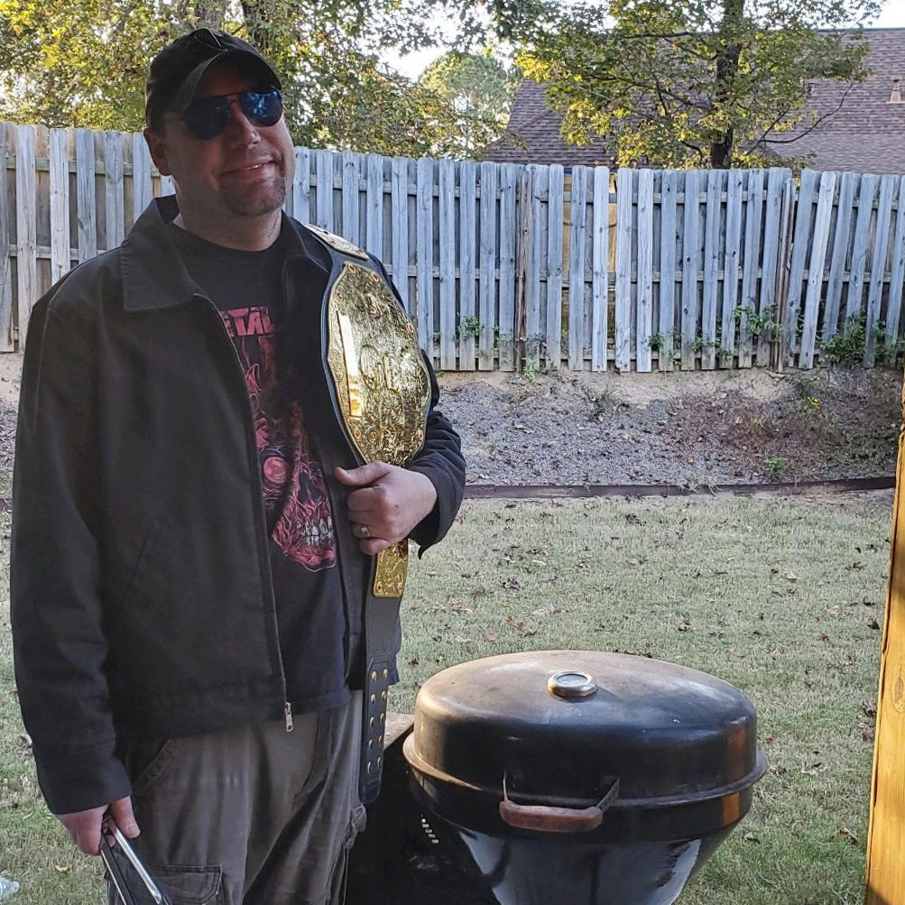 recteq customer service representative, Adam Doolittle, in his backyard with his wrestling belt and grilling on his RT-B380 Bullseye wood pellet grill.