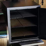 Smokebox RT-1250 & RT-700 attached to grill with door open showing the 3 shelves inside.